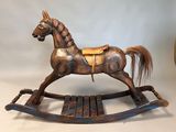 a wooden rocking horse with a saddle on it ' s back