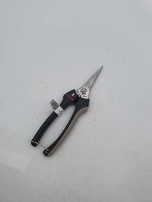 une paire de ciseaux posée sur une surface blanche, à côté d'une brosse à dents