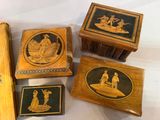 four wooden boxes with black and gold designs on them sitting on a table
