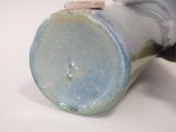 a close up of a vase with a handle on a table