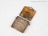 a silver cigarette case with a picture of a castle on it