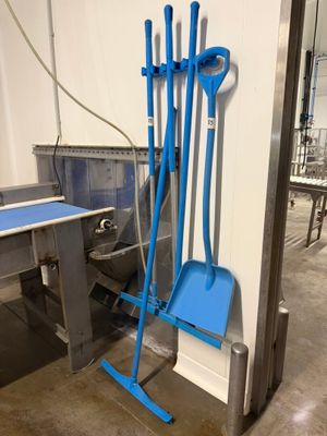 un balai bleu et une pelle bleue posés à côté d'une table