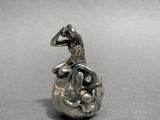a silver figurine of a bird sitting on top of an egg
