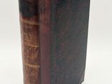 an old book sitting on top of a white table next to a white wall