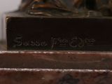 a bronze statue of a woman sitting on top of a table