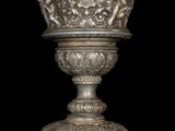 a silver vase that is sitting on a stand