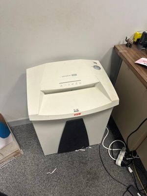 une déchiqueteuse à papier posée par terre à côté d'un bureau