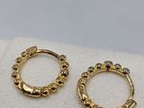 a pair of gold plated hoop earrings on a white cloth