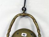 une petite horloge en laiton accrochée à un crochet au mur