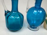 two blue glass vases sitting next to each other on a table