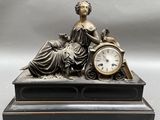une statue de femme assise au sommet d'une horloge