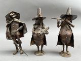 three metal figurines of a man and woman playing instruments