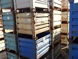 many blue crates stacked on top of each other in the dirt