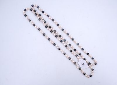 un gros plan d'un collier composé de perles blanches et noires, posé sur une surface blanche