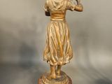 bronze statue of a woman holding a flower on a marble base