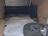 the inside of a van with a mattress and a tire in the back