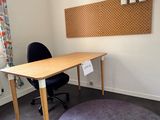 un bureau avec une chaise et un tableau en liège accroché au mur