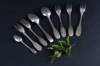 a set of six forks and spoons with leaves on a black surface