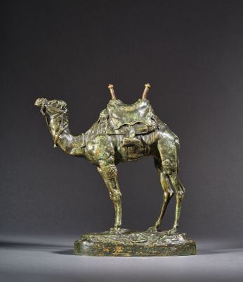 une statue en bronze représentant un chameau avec une selle sur le dos