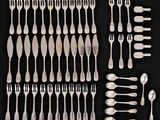 many forks and spoons laid out on a black surface