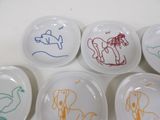 four white plates with drawings of animals on them on a table