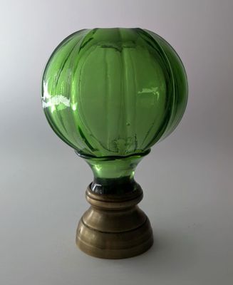 un vase en verre vert posé sur une table, avec un socle en bois