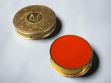 une pièce d'or et un bouton rouge sur un fond blanc