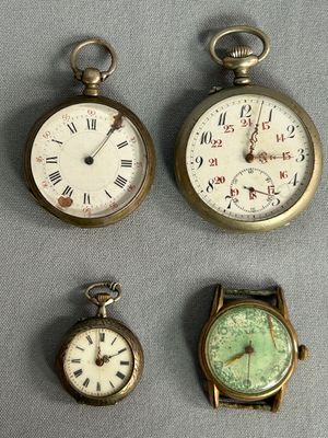 Quatre types différents de montres de poche sont exposés sur un support gris.