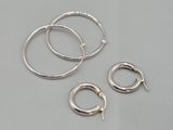 un lot de trois boucles d'oreilles en argent en forme d'anneaux posé sur une table