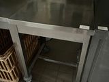 a large stainless steel table in a kitchen with baskets on the floor