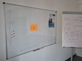 un tableau blanc sur lequel sont écrites des notes, à côté d'un autre tableau blanc sur lequel sont écrites des notes