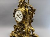 une horloge en or posée sur une table blanche