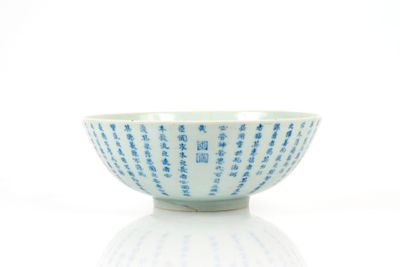 un bol bleu et blanc orné d'une inscription, posé sur une surface blanche