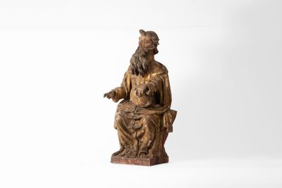 une vieille statue en bois représentant un homme assis sur une chaise