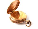 a gold pocket watch with a chain on a white surface