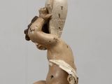 a statue of a baby holding a lamp on a table