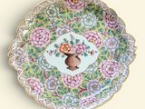 une assiette décorative sur laquelle figurent des fleurs et un vase
