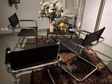chairs and a table in a room with a rug and a vase of flowers