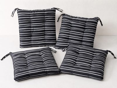quatre coussins rayés noir et blanc posés sur une surface blanche