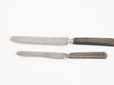 two knives are sitting next to each other on a white surface