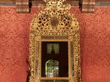 a mirror sitting on a mantle in front of a red wall