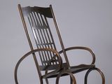 un vieux fauteuil à bascule avec une assise en bois posée sur une surface blanche