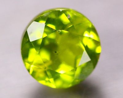 un gros plan d'une pierre précieuse verte sur une surface blanche