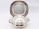an antique silver plated casserole with a lid on a white surface