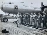black and white photo of a group of men standing in front of an airplane