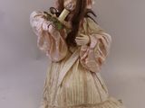 une statue représentant une femme en robe et coiffe, tenant une banane