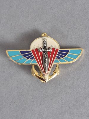une image représentant un pin's rouge, blanc et bleu orné d'une épée