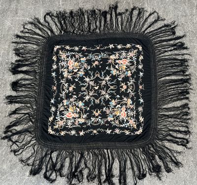 carré noir et blanc avec des franges et des fleurs sur un tapis