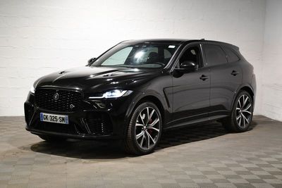 Le SUV noir est garé dans une grande pièce au sol carrelé en damier.