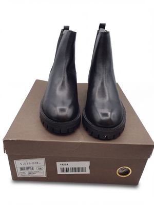 des bottines en cuir noir à semelles en caoutchouc, présentées dans une boîte